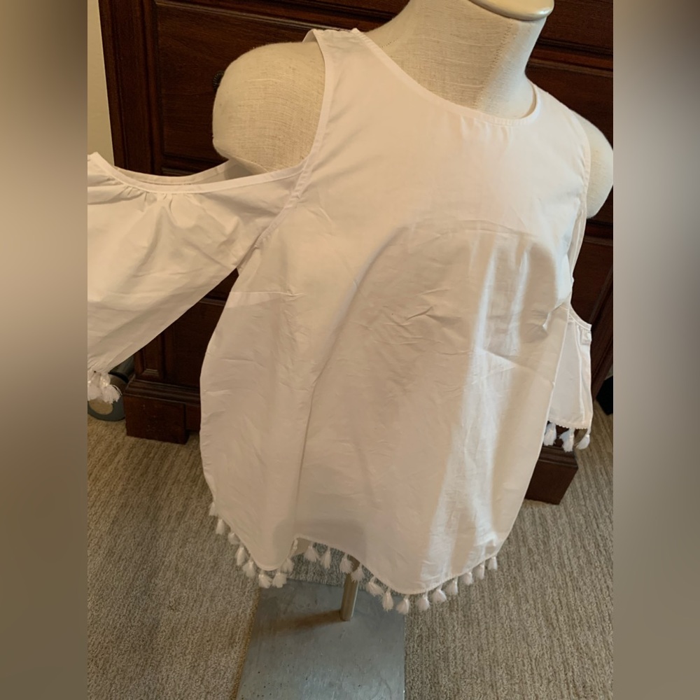 Crisp, white blouse, cold shoulder with little pom-poms on the sleeves and hem.